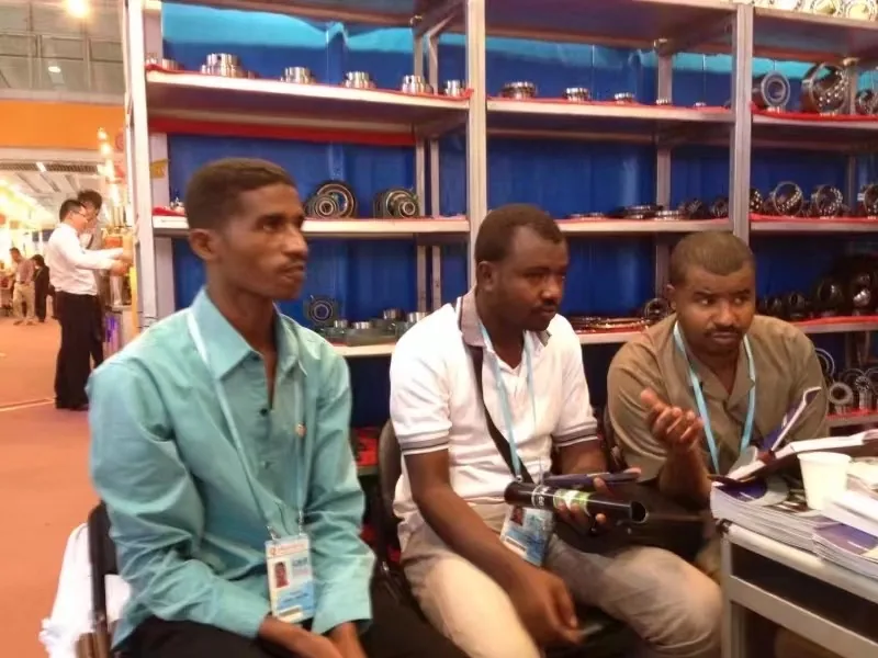 Three overseas customers seated at the FULI booth in front of shelves of bearing samples