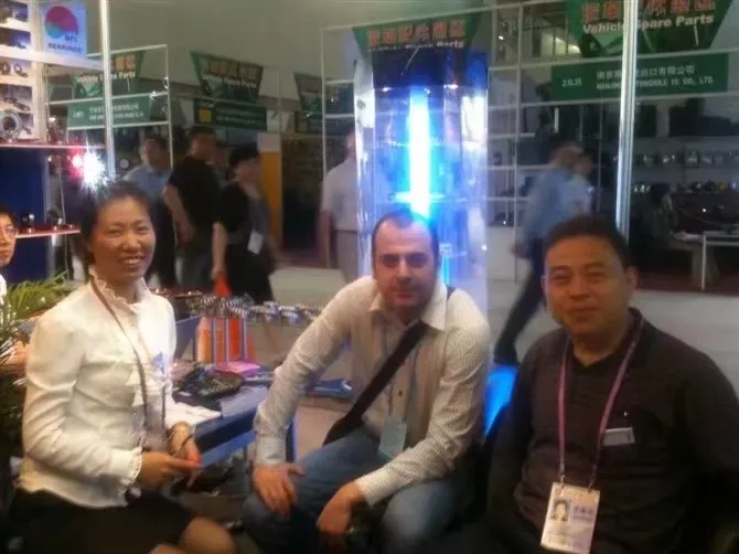 Two FULI staff talking with a visitor seated at a trade fair booth