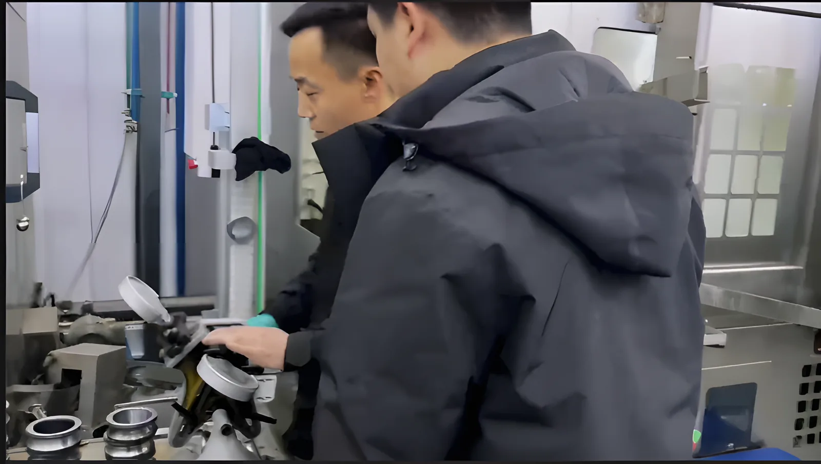 Two FULI staff checking a bearing ring on a dial gauge fixture in the Linqing workshop