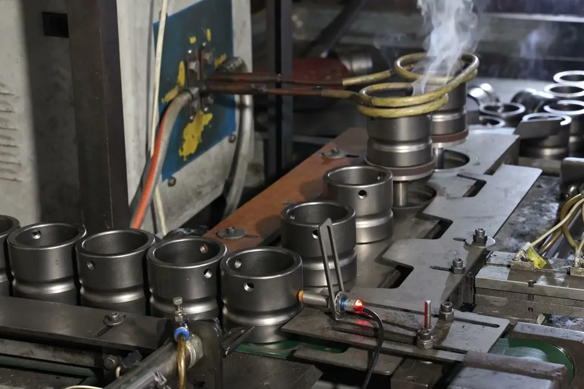 An induction coil heating a steel ring blank, with more blanks lined up on the machine bed